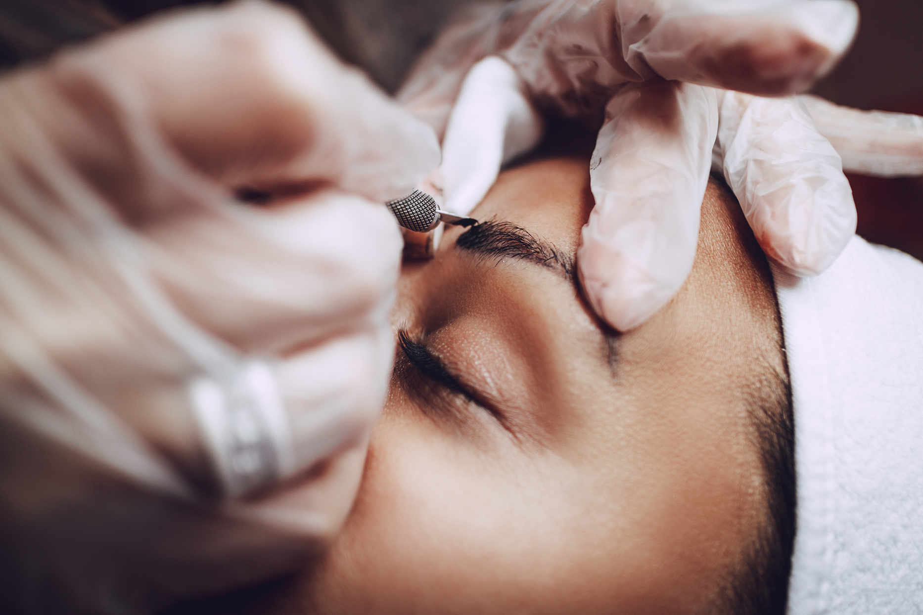Closeup of beautician applying permanent makeup to brows